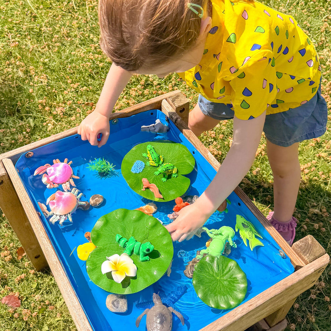 Child playing with water and toy animals with lilipads